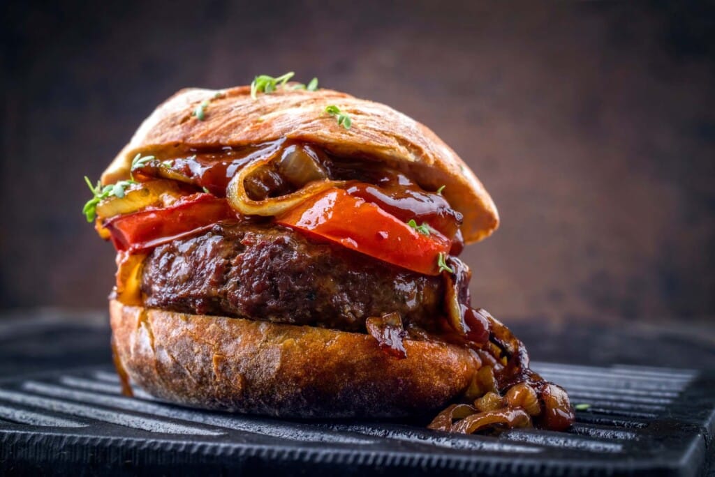 Herzhafte Kornelkirschen-Burger mit geschmolzenem Cheddar und karamellisierten Zwiebeln